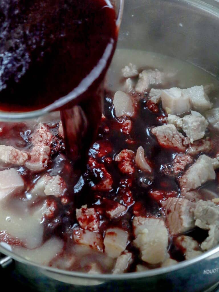 pouring blood in pork stew in a pot
