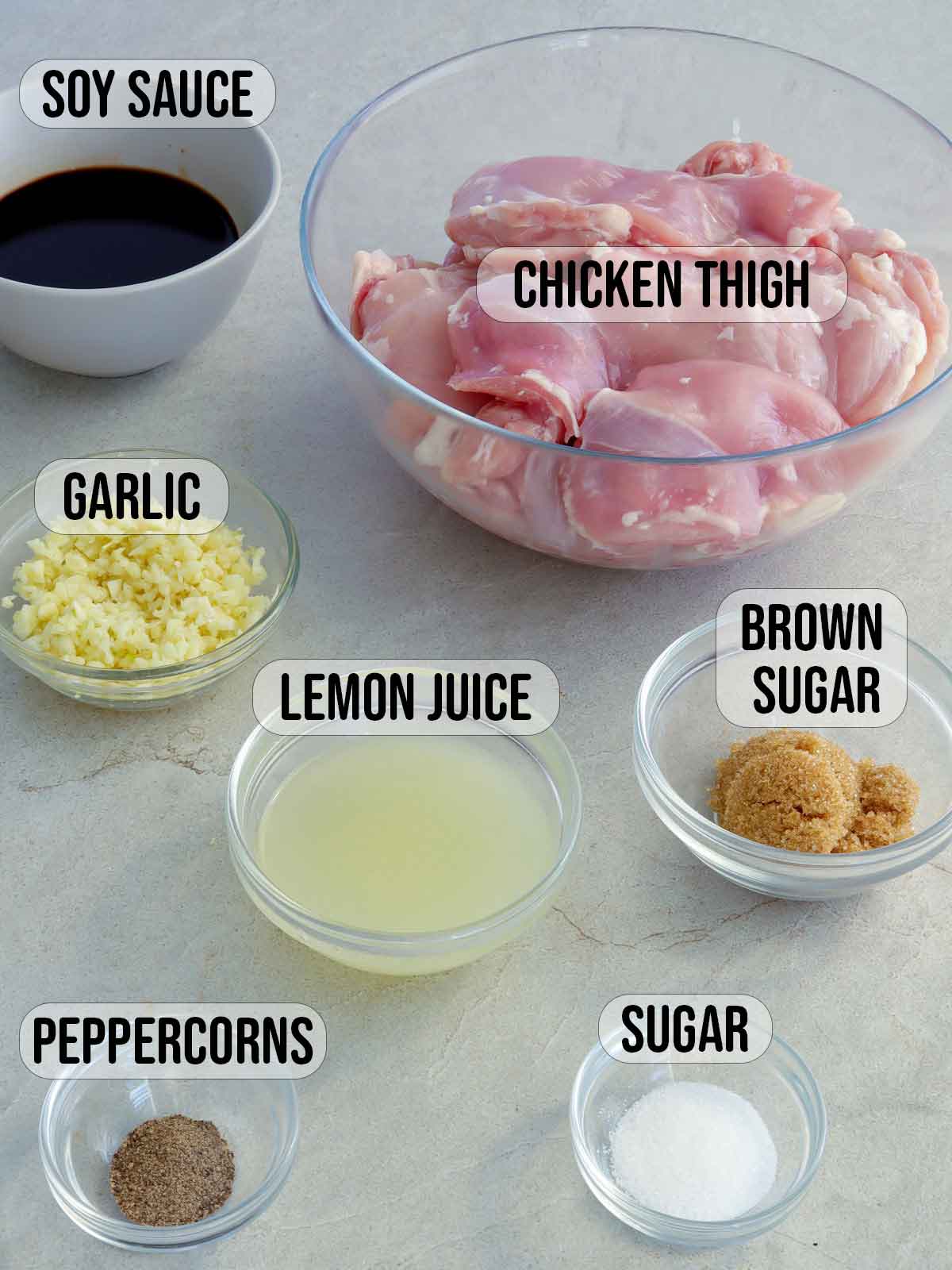 boneless chicken thigh meat, garlic, lemon juice, brown sugar, soy sauce, pepper, salt in bowls.