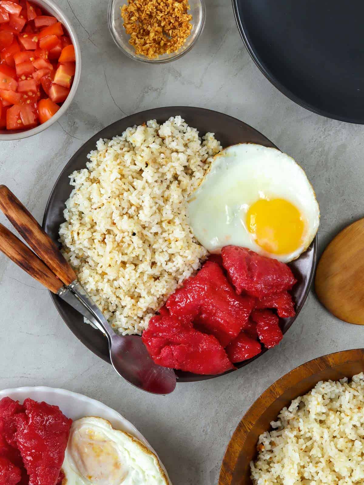 Filipino garlic rice on a black plate with tocino and fried egg