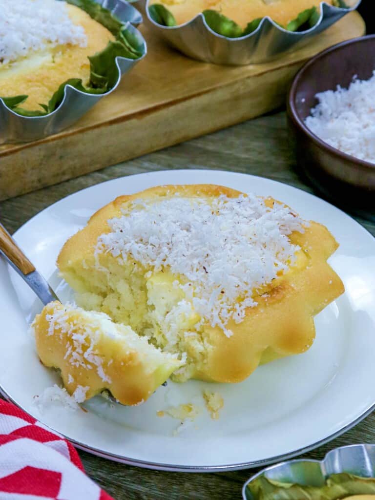 cut bibingka with grated coconut topping on a blue serving plate