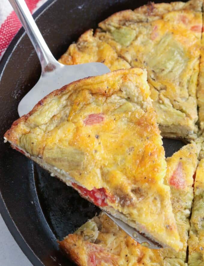 serving a slice of eggplant and tomato frittata from a cast iron skillet.