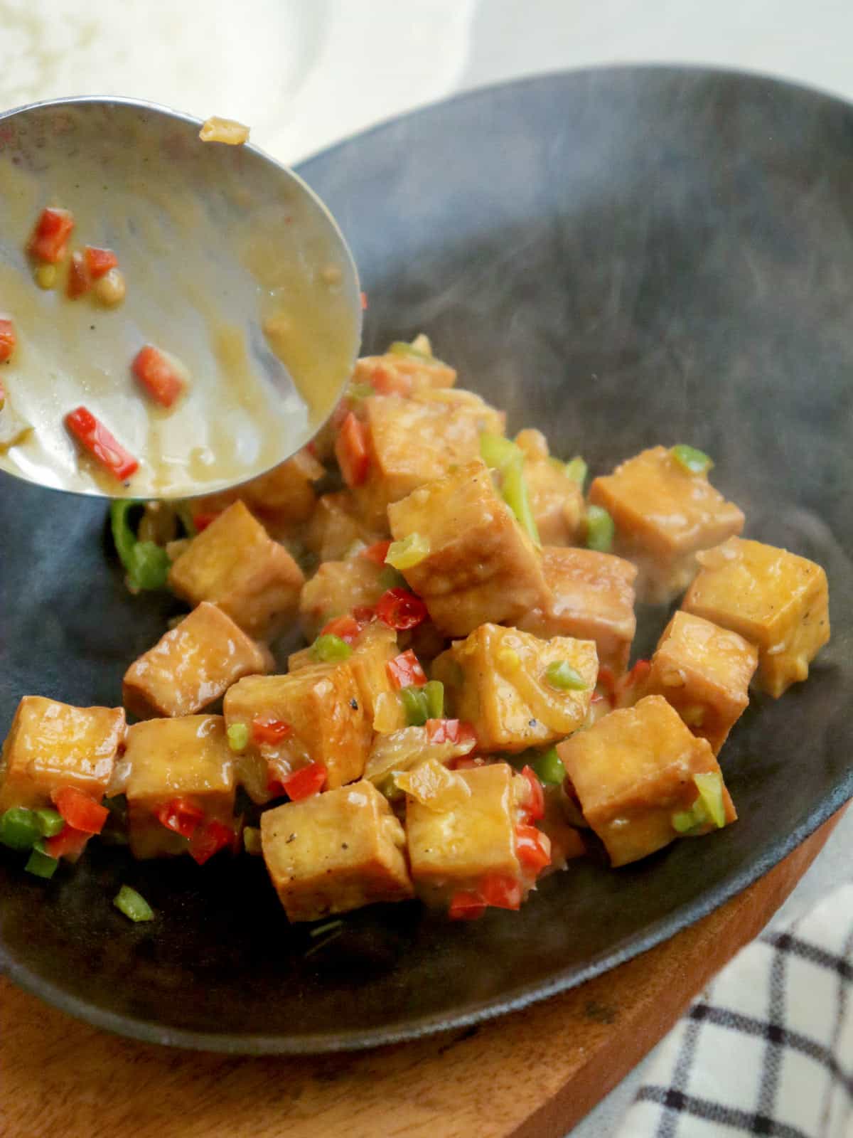 placing sisig tofu on a hot sizzling plate