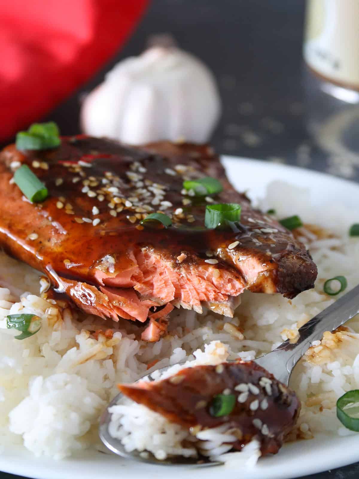 eating teriyaki Salmon over steamed rice on a black plate