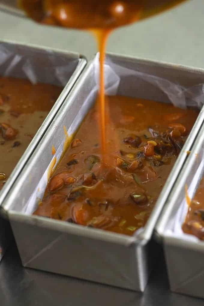 pouring fruitcake batter into aluminum baking pans