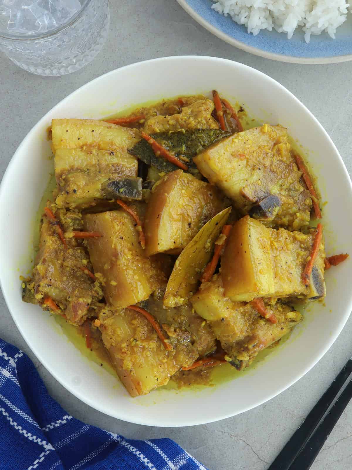 yellow adobo in a white serving bowl