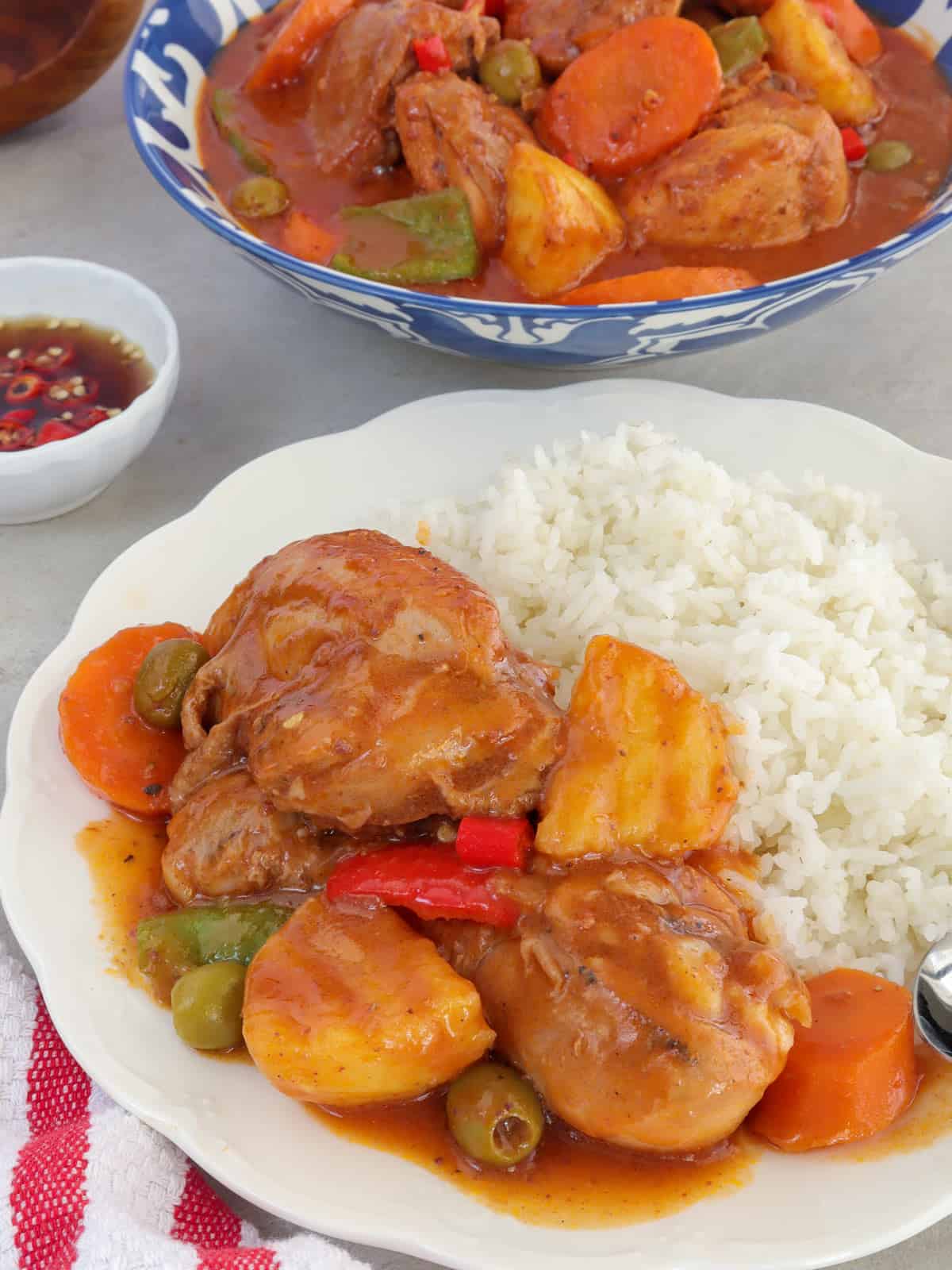 chicken caldereta with steamed rice on a white plate.