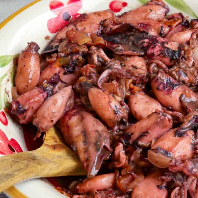 Ginisang Pusit in a serving bowl with a wooden spoon