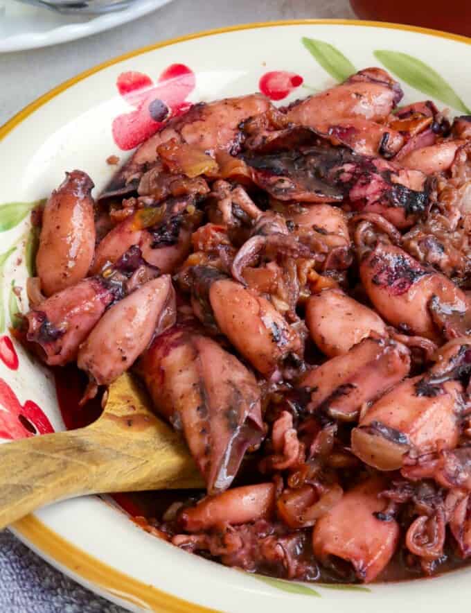 Ginisang Pusit in a serving bowl with a wooden spoon