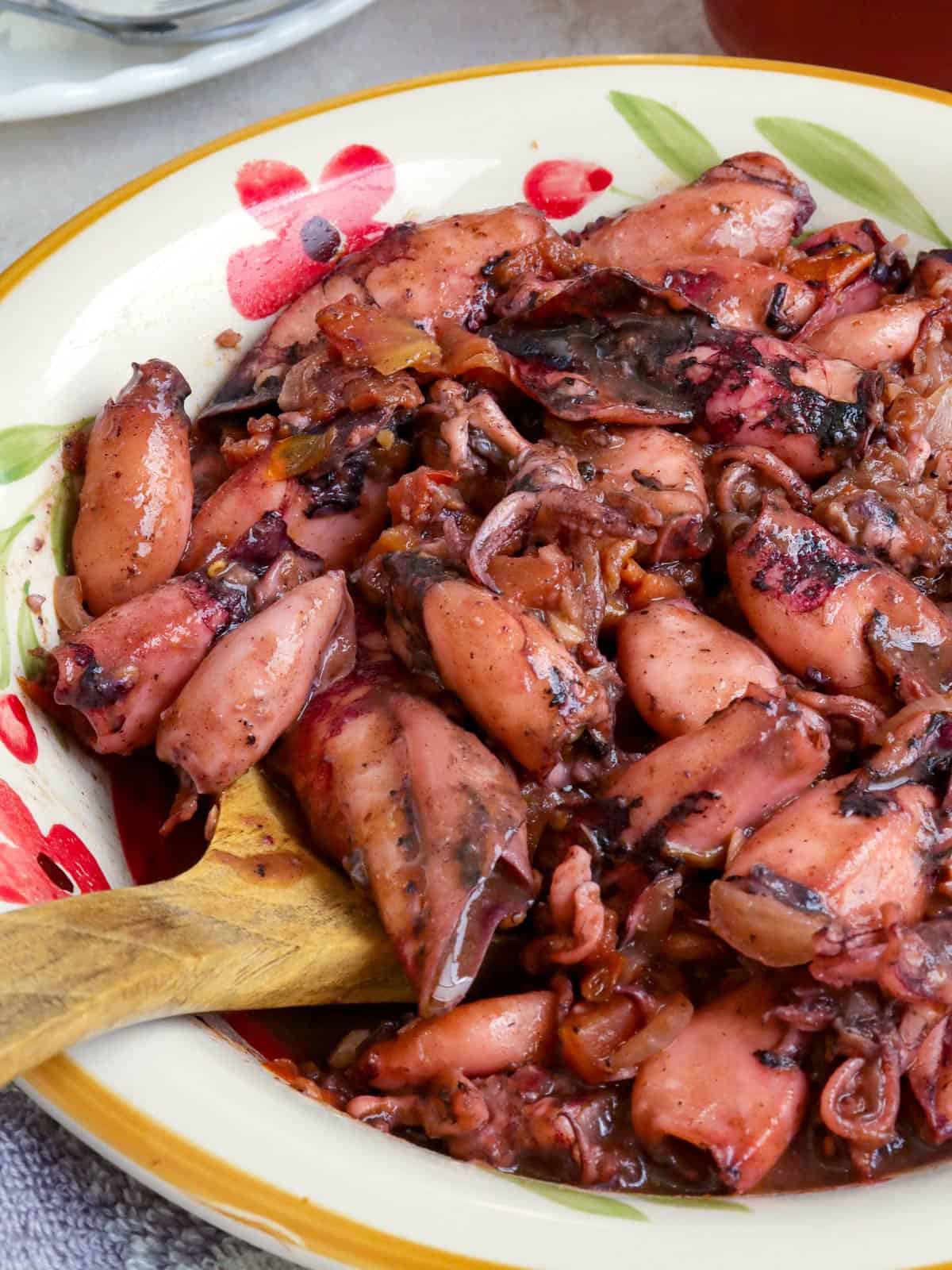 Ginisang Pusit in a serving bowl with a wooden spoon