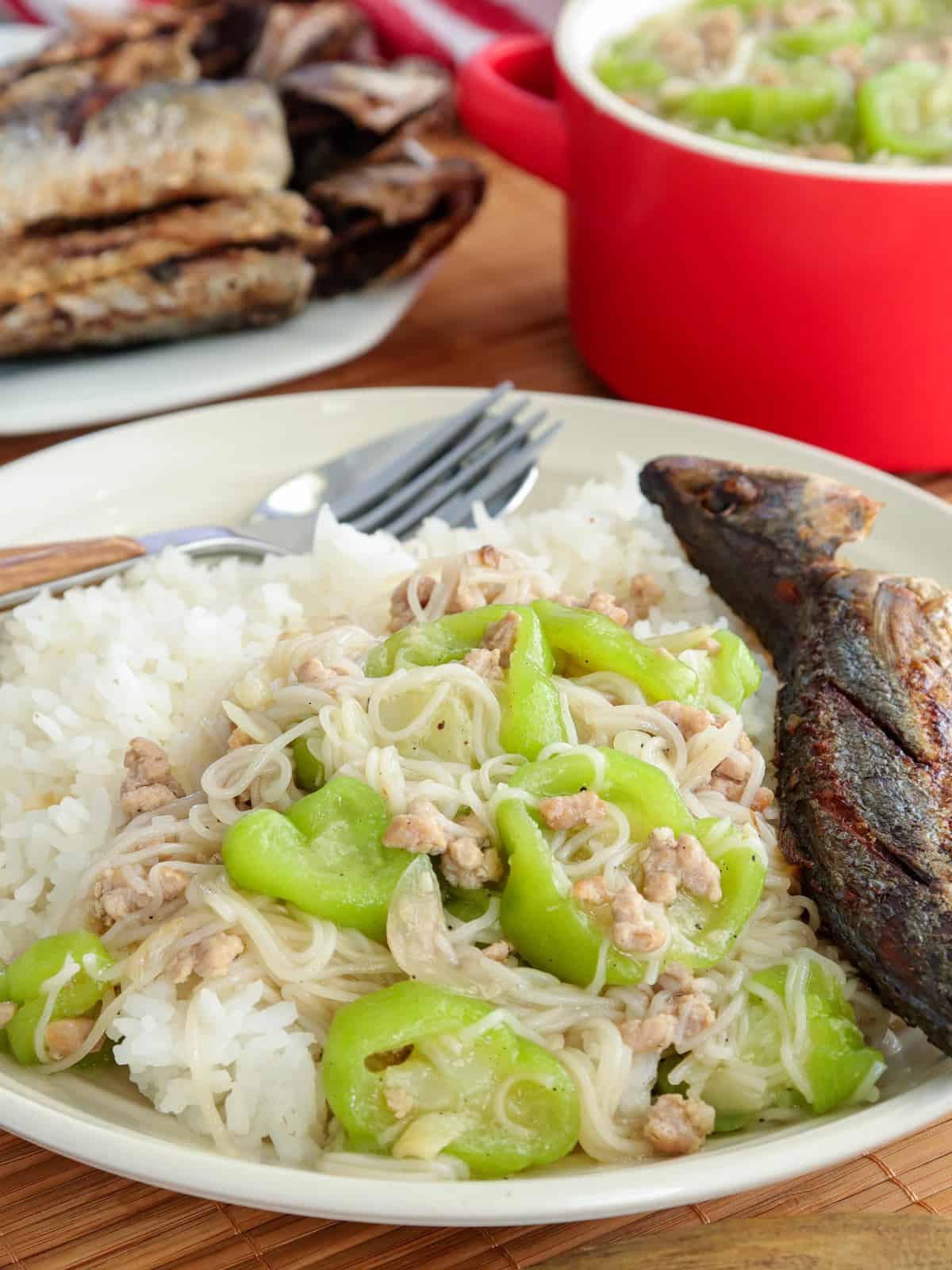 patola and miswa over rice with fried fish on a plate