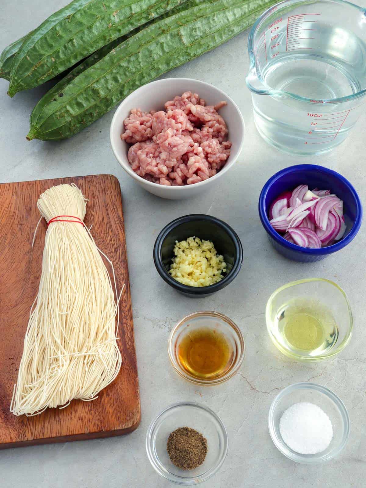 ingredients for soup-patola, miswa, ground pork, fish sauce, water, onions, garlic, oil, salt, and pepper in bowls