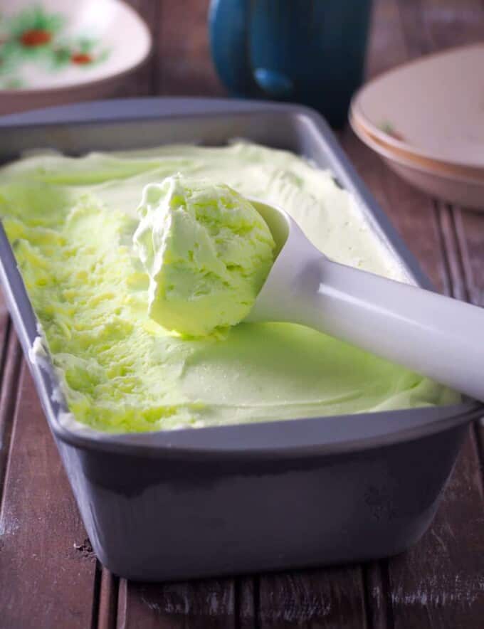 scooping buko pandan ice cream from a metal loaf pan