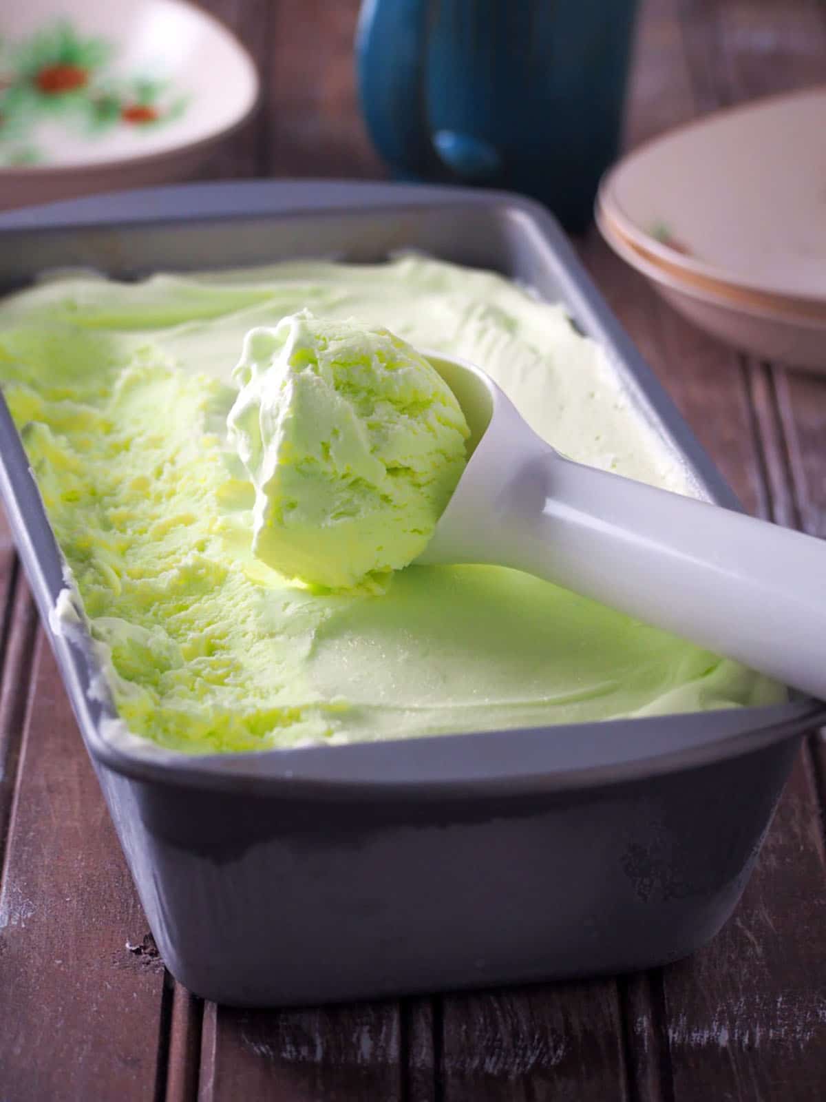 scooping buko pandan ice cream from a metal loaf pan