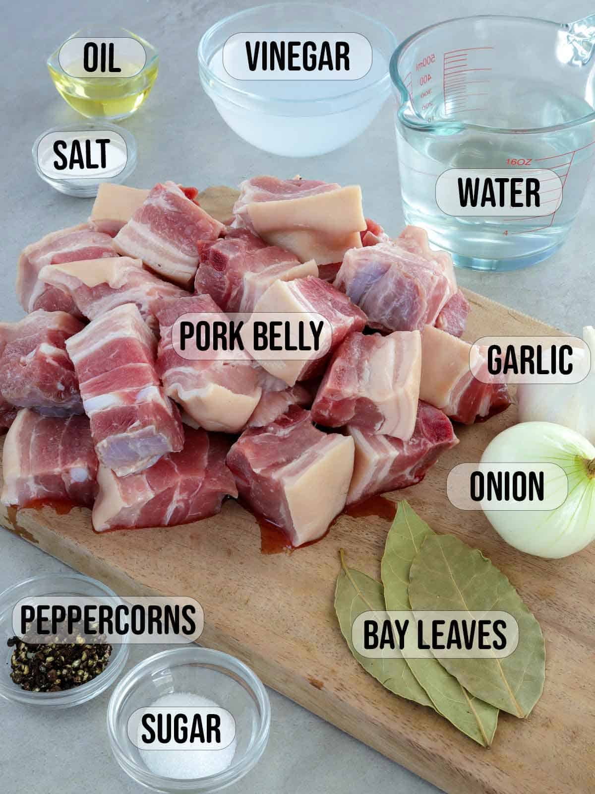 pork belly cubes, bay leaves, onions, garlic, peppercorns, salt, vinegar, oil, water, sugar.