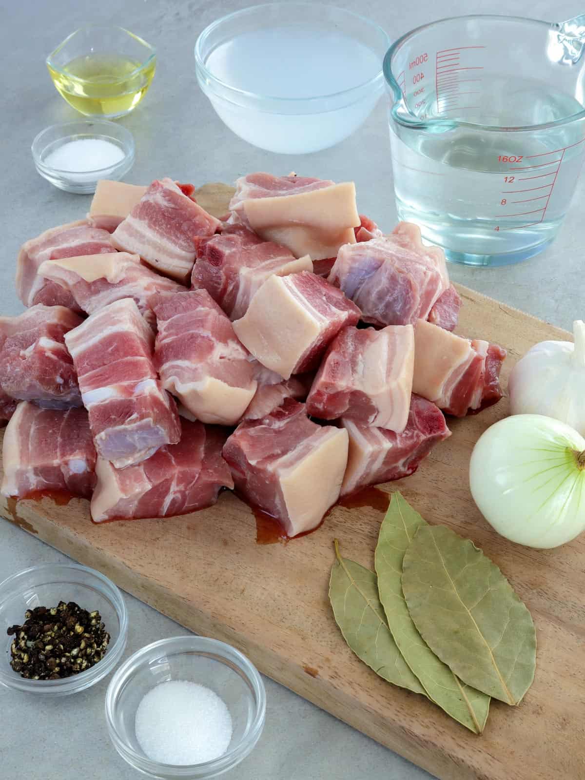 pork belly cubes, bay leaves, onions, garlic, peppercorns, salt, vinegar, oil, water, sugar