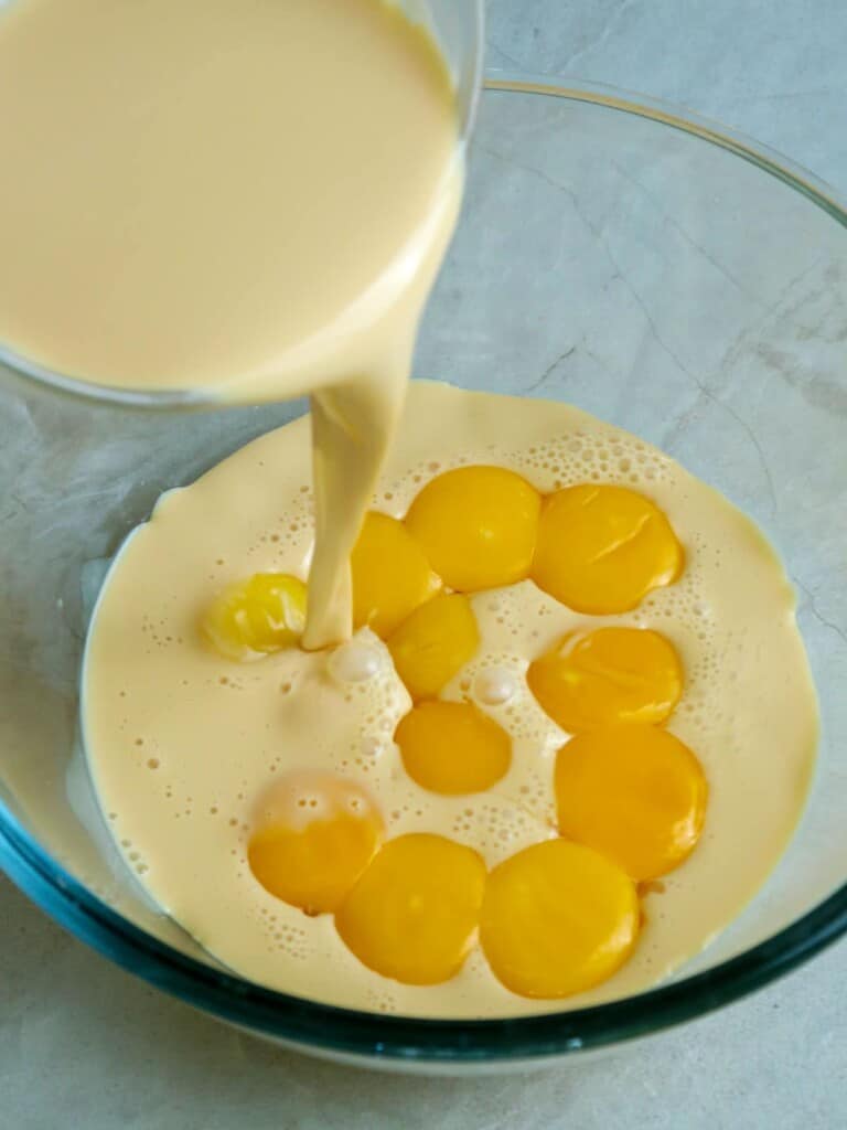 yolks, condensed milk, and evaporated milk mixture in a bowl