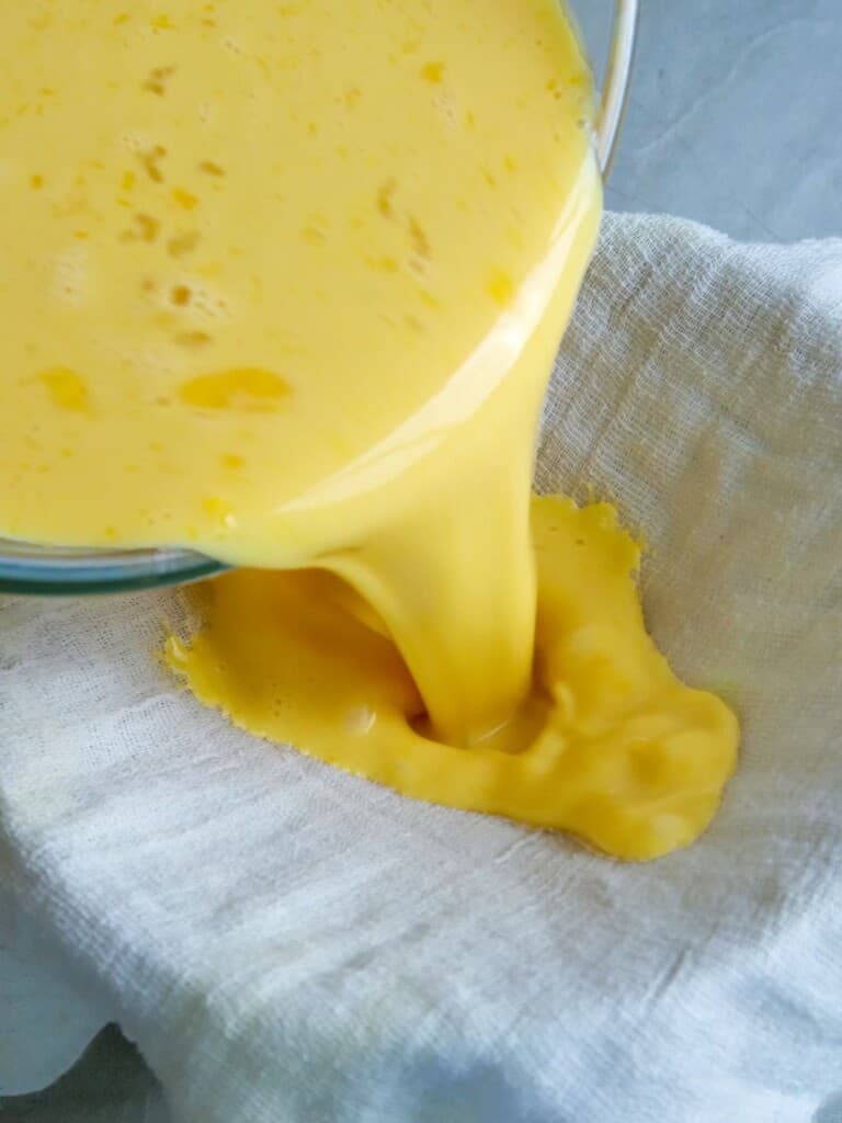 straining egg custard with a cheesecloth