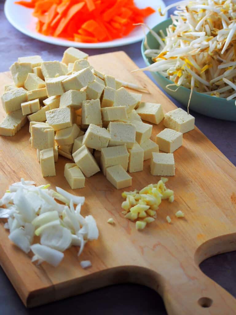 cubed tokwa,chopped onions, minced garlic on a cutting board