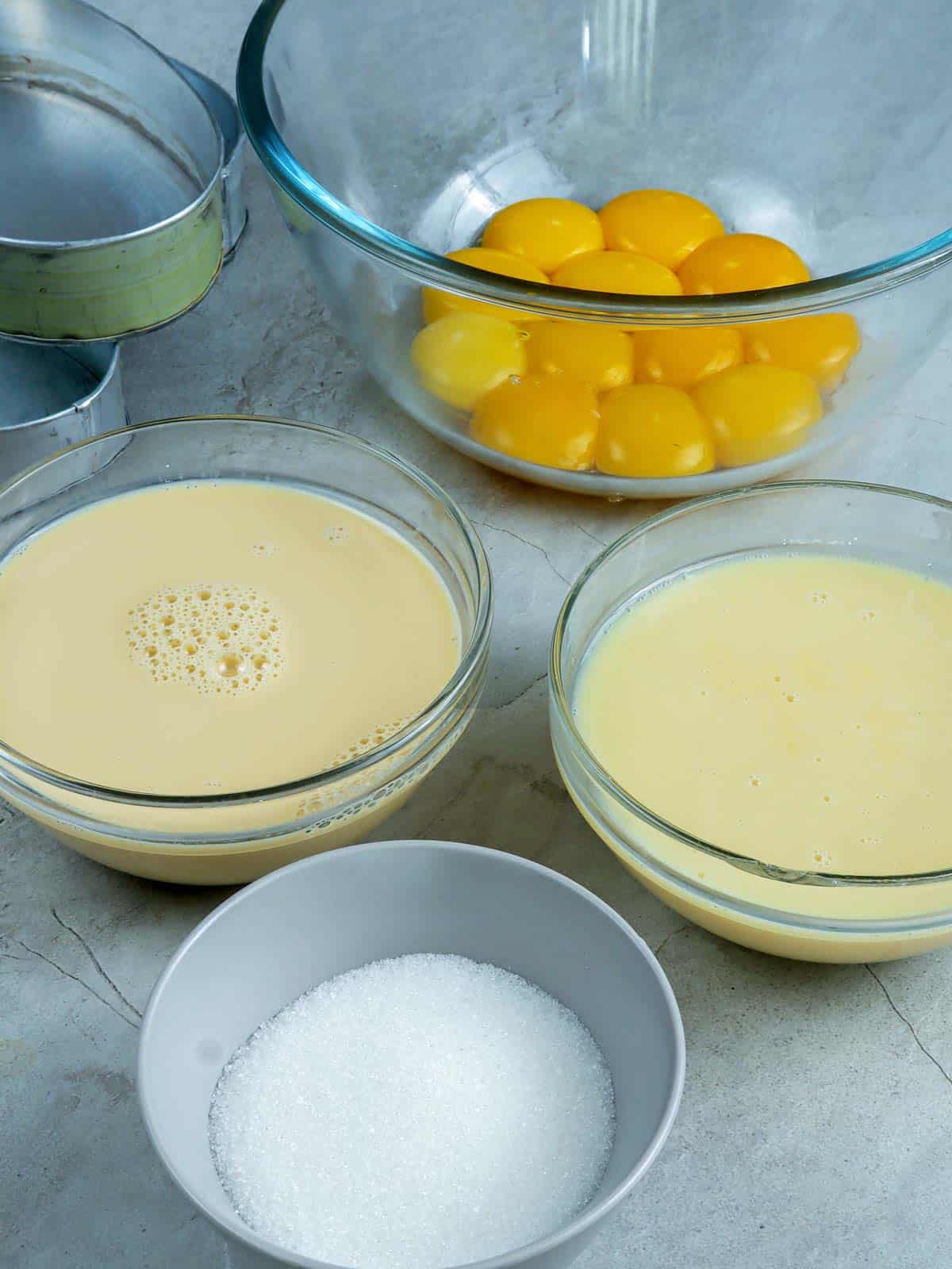 egg yolks, sugar, evaporated milk, condensed milk in bowls