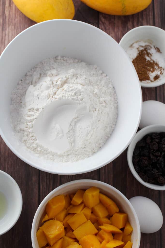 flour, mangoes, raisings, sugar, cinnamon in bowls