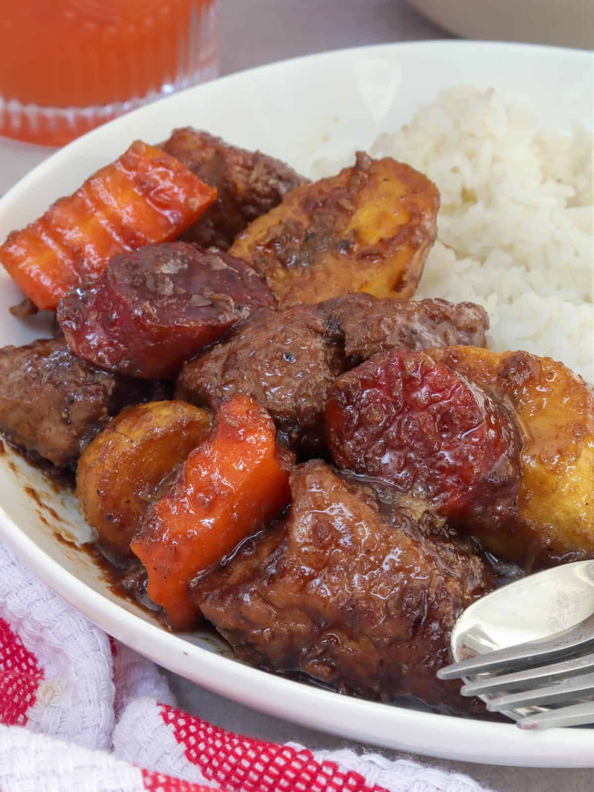 estofadong baboy on a plate with steamed rice