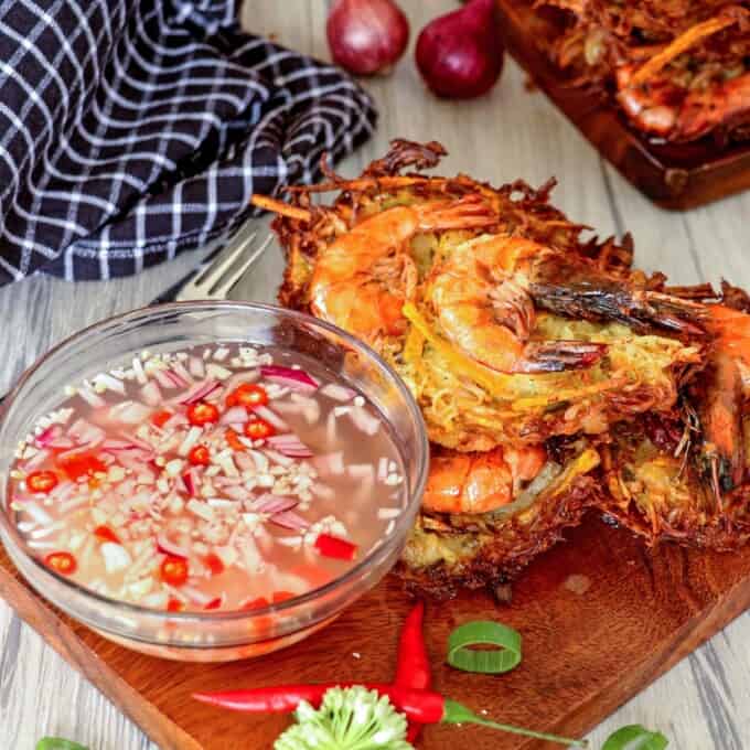 crispy ukoy made with papaya on a wooden board with spicy vinegar in a bowl on the side