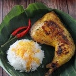 inasal na manok on a banana-lined plate with steamed rice and chili peppers