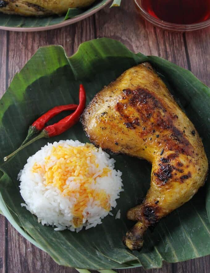 inasal na manok on a banana-lined plate with steamed rice and chili peppers