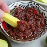 dipping sliced green mangoes in a bowl of ginisang bagoong