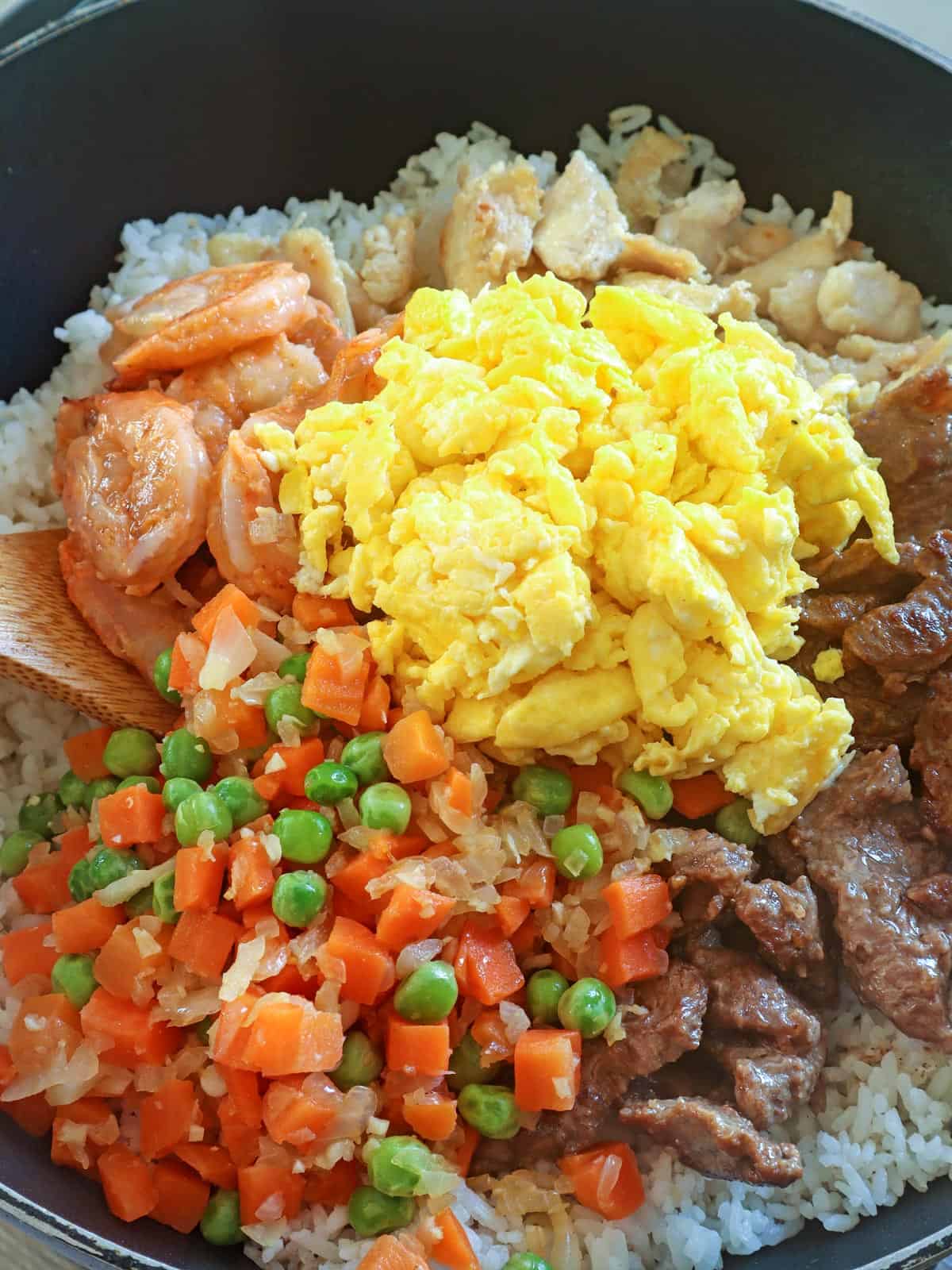 cooking stir-fried with shirmp, eggs, peas and carrots, chicken, and beef in a pan