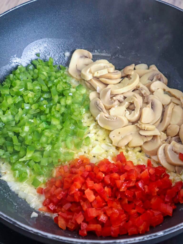 sauteing peppers, onions, and sliced mushrooms in a pan