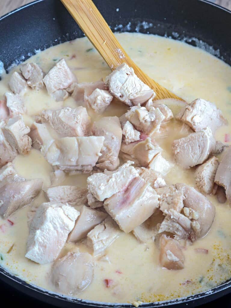 poached chicken breast added to creamy sauce in a pan