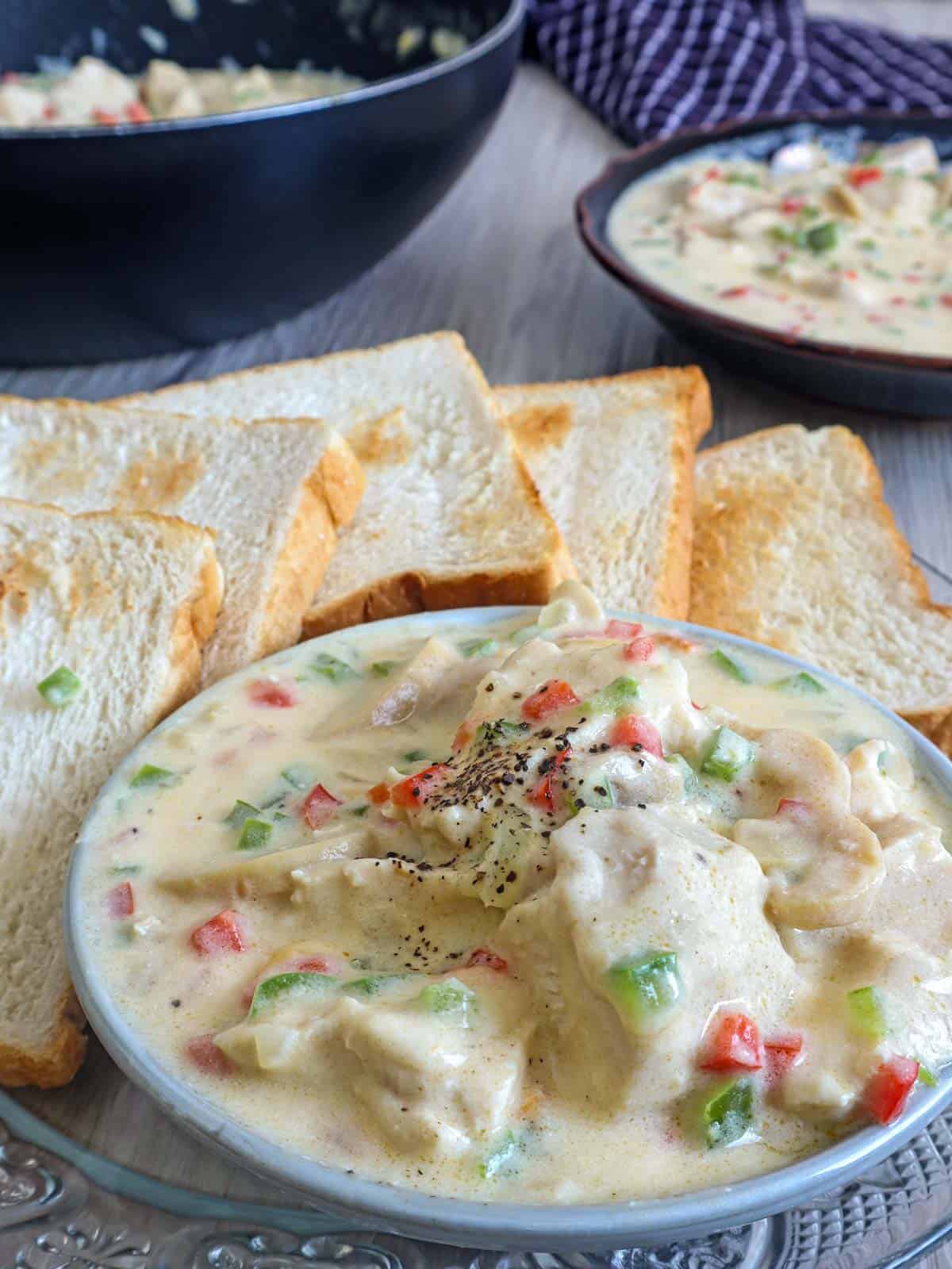 chicken a la king in a bowl with toasted bread on the side