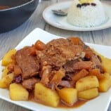 Pineapple Pork Ribs on a white plate with a plate of steamed rice on the side