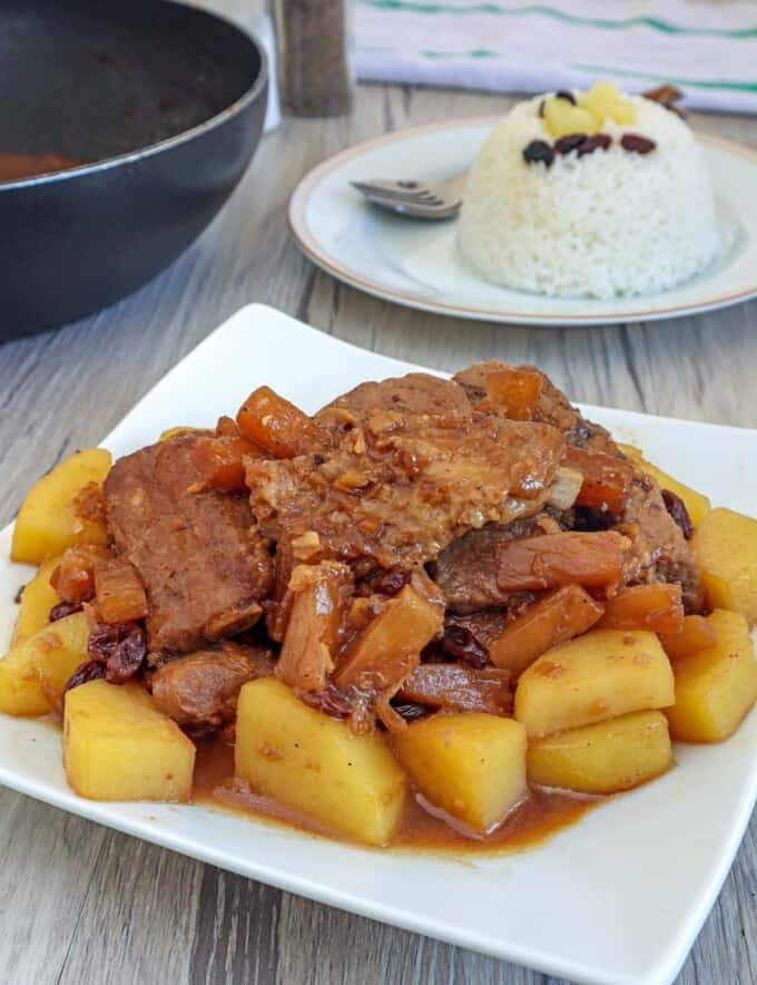 Pineapple Pork Ribs on a white plate with a plate of steamed rice on the side