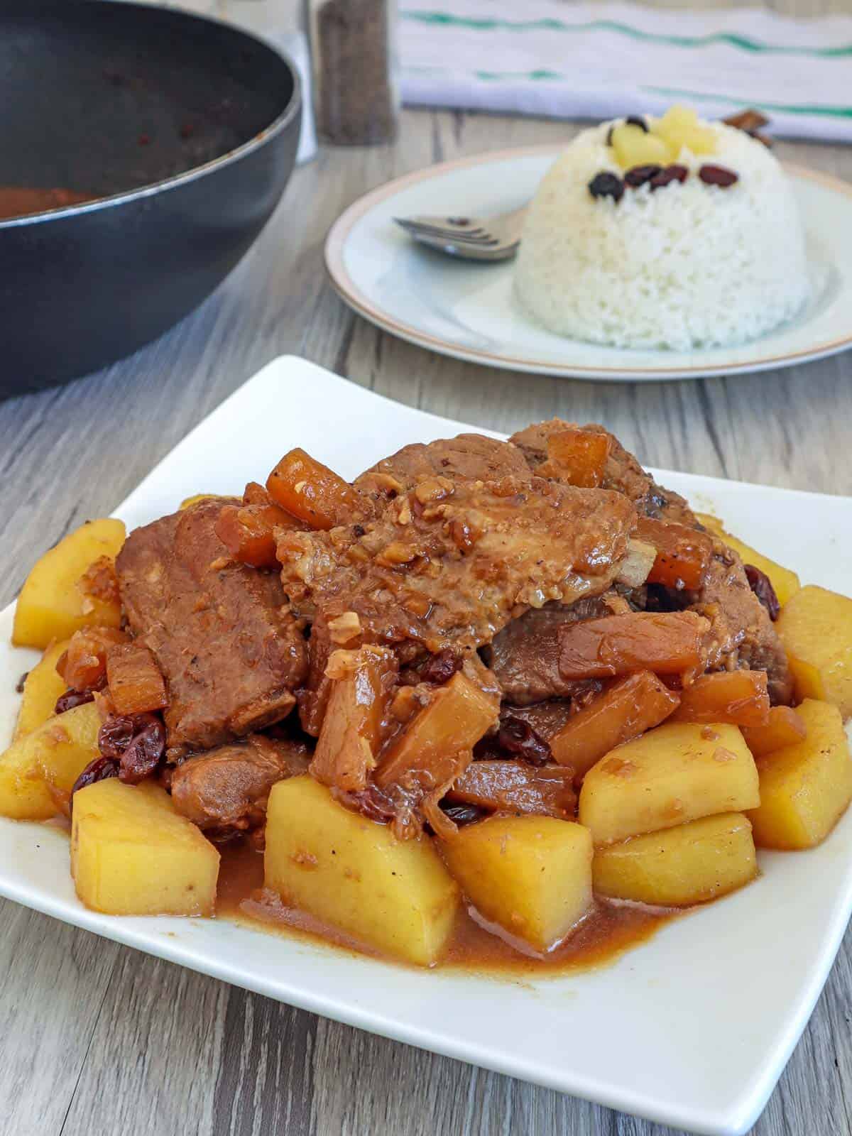 Pineapple Pork Ribs on a white plate with a plate of steamed rice on the side