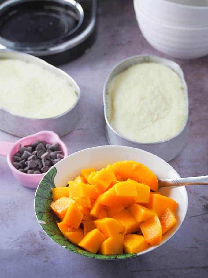 mango cubes in a bowl with chocolate chips and chiffon cake batter in llaneras on the side