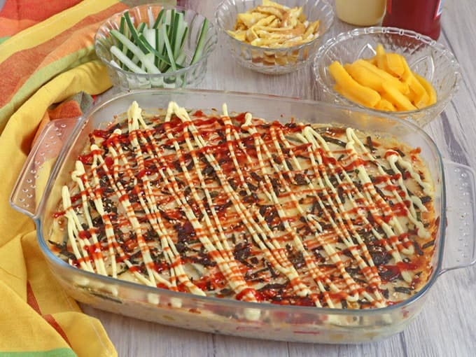 sushi bake in a casserole with drizzles of mayo and Sriracha