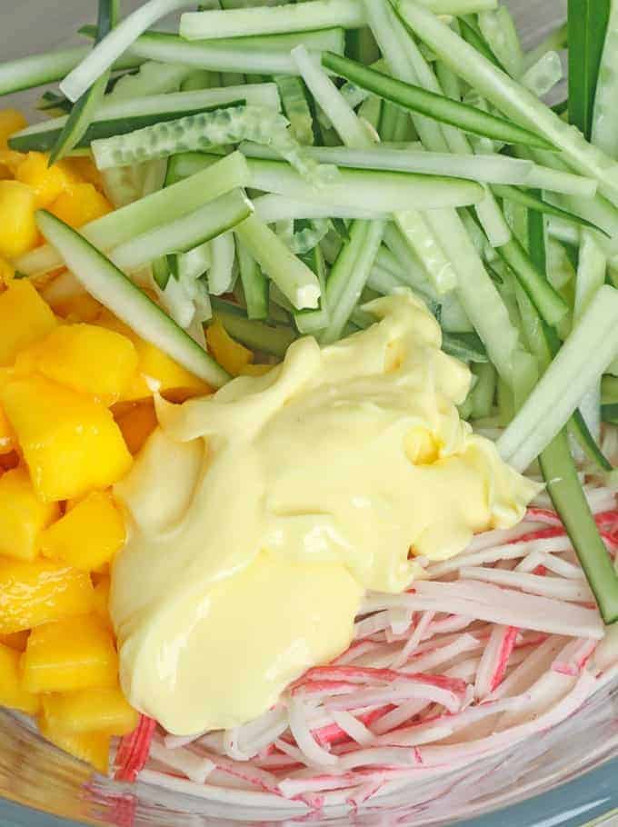 shredded kani, diced mangoes, cucumber strips, and Japanese mayo in a bowl