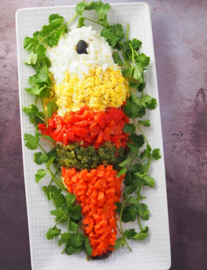 Steamed Lapu-Lapu with Mayonnaise garnished with chopped eggs, roasted bell peppers, sweet relish, and chopped carrots on a platter