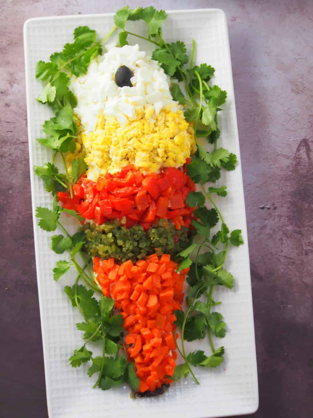 Steamed Lapu-Lapu with Mayonnaise garnished with chopped eggs, roasted bell peppers, sweet relish, and chopped carrots on a platter