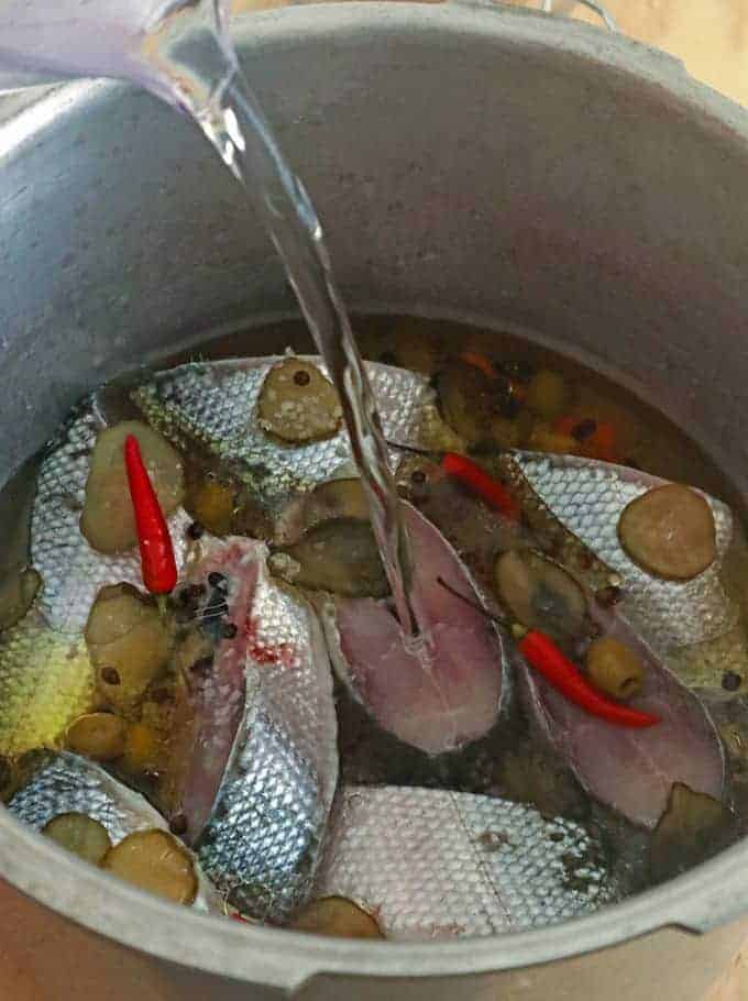 pouring water over bangus in a pressure cooker