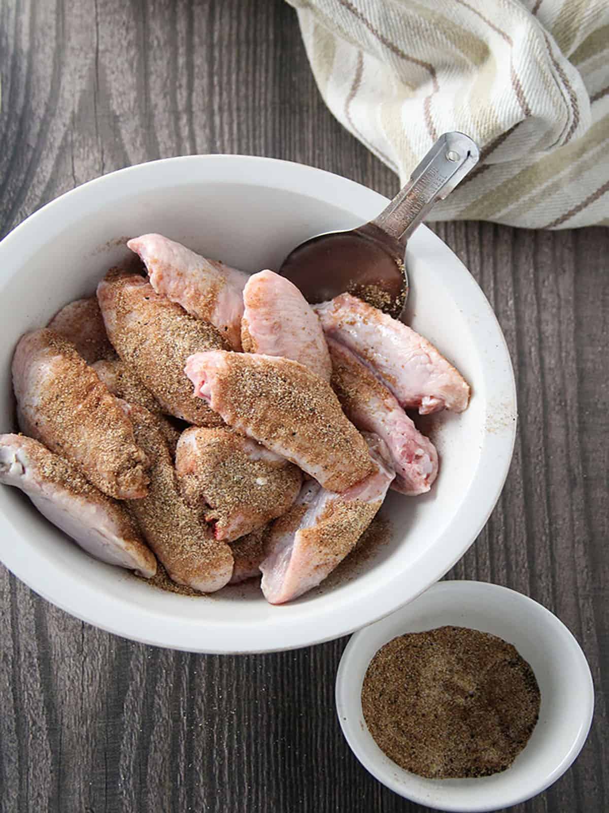 chicken wings seasoned with tamarind powder, garlic powder, salt, and pepper in a white bowl