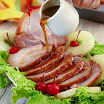 pouring pineapple glaze on sliced homemade holiday ham