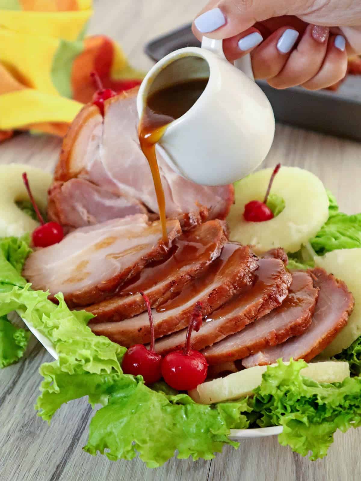 pouring pineapple glaze on sliced homemade holiday ham