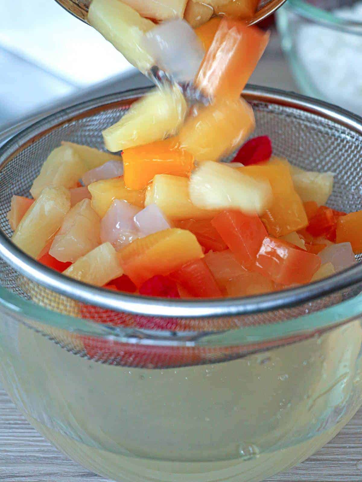 draining canned fruit cocktail in a bowl using a fine-mesh sieve