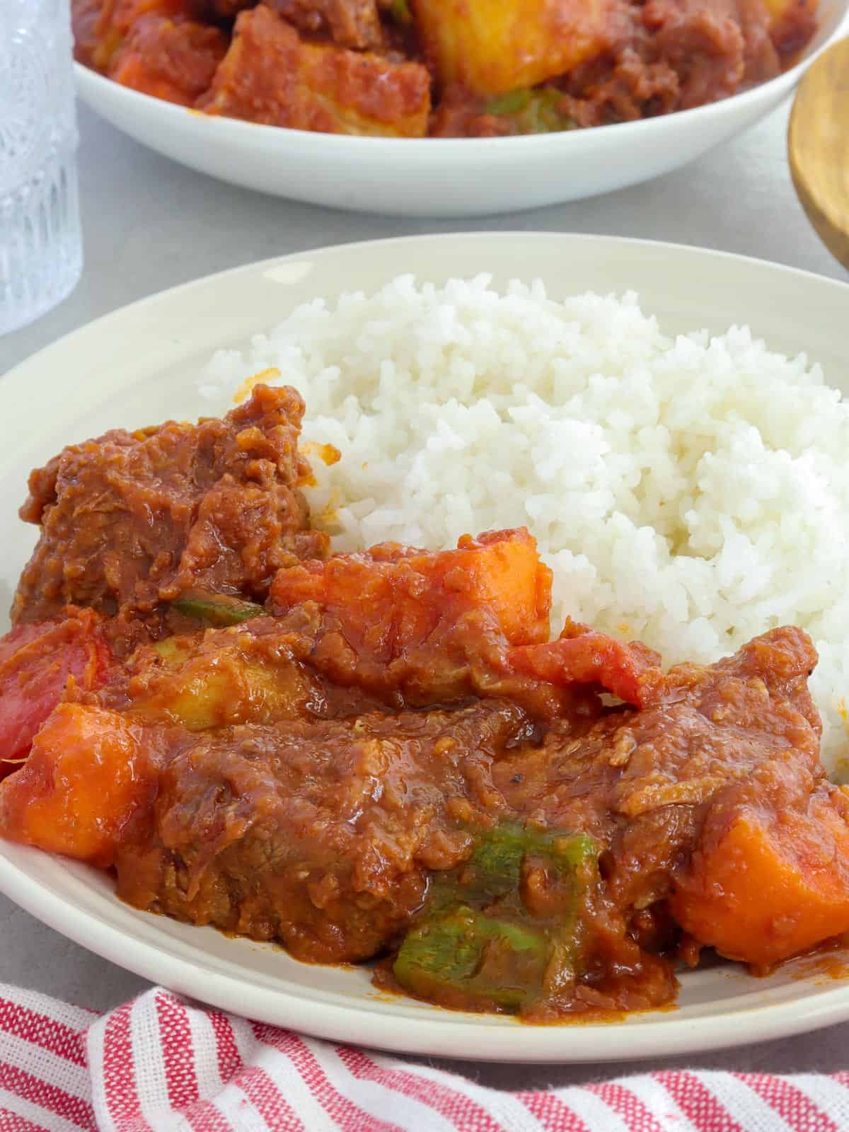 afritadang baka on a white plate with steamed rice