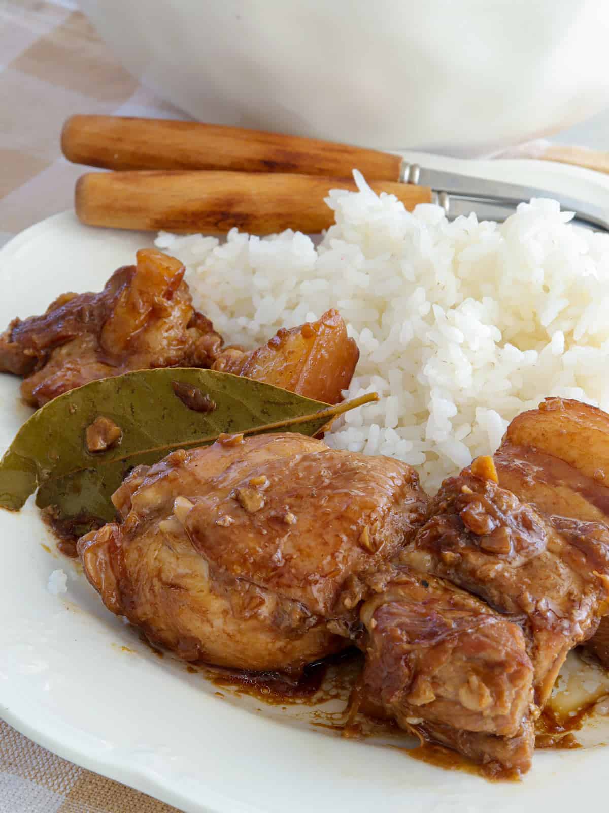 adobong manok at baboy over steamed rice on a white plate.