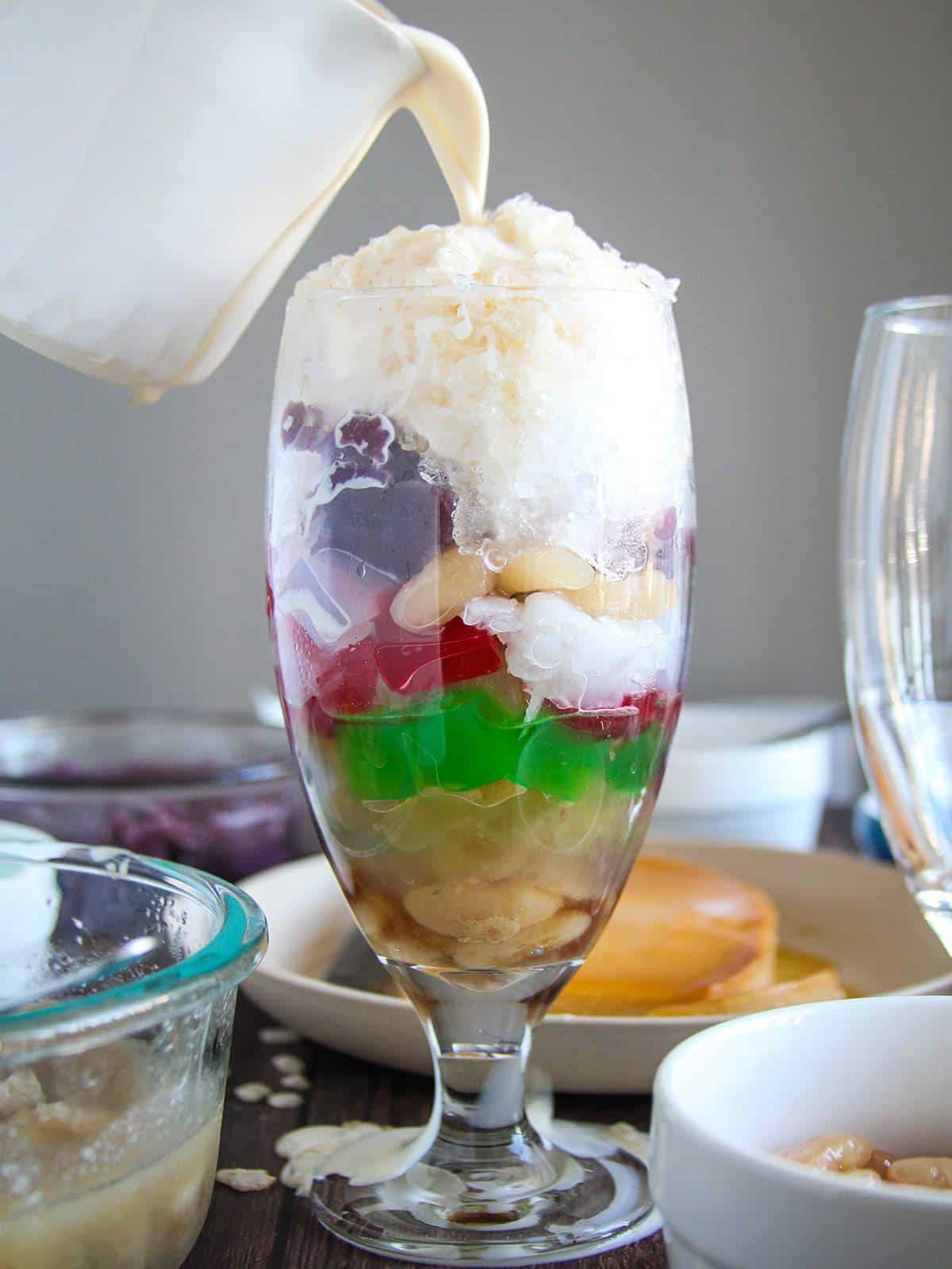 pouring evaporated milk in a glass of halo-halo