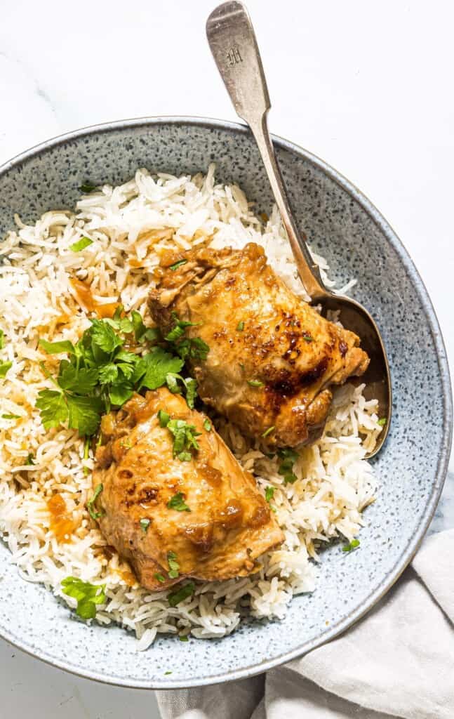 pressure cooker adobong manok on a bed of steamed rice in serving bowl